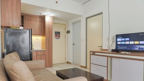 A compact living space with a kitchenette, a sofa, a coffee table, and a television displaying streaming services.