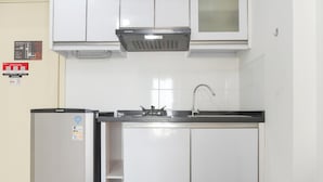 A compact kitchen with white cabinets, a stainless steel refrigerator, and a built-in oven. - Homey And Modern Design 2Br Apartment At M-Town Residence (Gading Serpong)