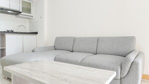 A modern kitchen with white cabinets, a grey sofa, and a marble coffee table. - Homey And Modern Design 2Br Apartment At M-Town Residence (Gading Serpong)