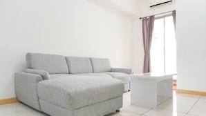 A modern living room with a grey sofa, a white coffee table, and a large window with curtains. - Homey And Modern Design 2Br Apartment At M-Town Residence (Gading Serpong)