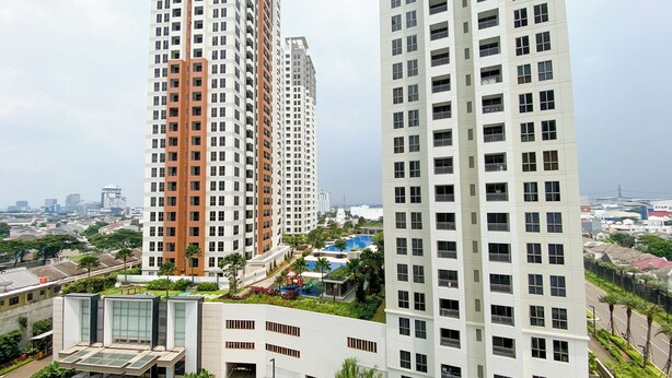 A high-rise residential building with multiple floors, balconies, and a rooftop pool area. - Homey And Modern Design 2Br Apartment At M-Town Residence (Gading Serpong)