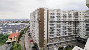 A high-rise residential building with multiple balconies, a parking area, and a view of the surrounding neighborhood.