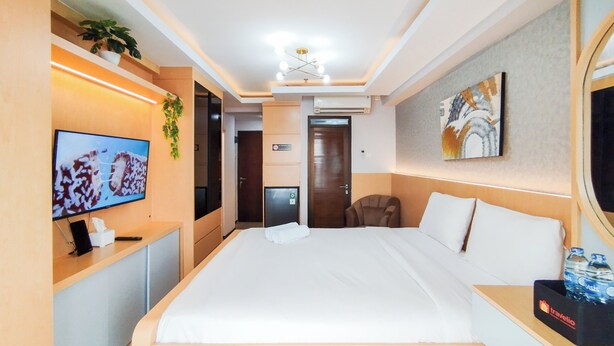 A hotel room with a bed, a TV, a desk, a chair, and a bathroom door.