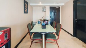 A dining area with a rectangular table, four chairs, a coffee machine, and a refrigerator.