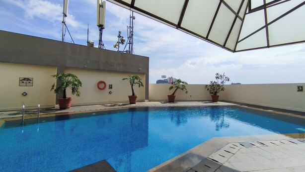An indoor swimming pool with a clear view of the sky and surrounding buildings.