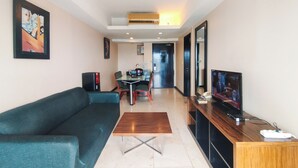 A modern living room with a sofa, a coffee table, a TV, and a dining area with chairs and a table.