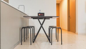 Une petite cuisine équipée avec une table, deux tabourets et une bouteille d’eau posée sur le comptoir.