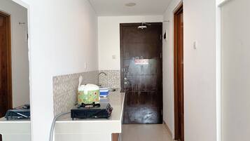 Un pasillo estrecho con una zona de cocina a un lado, que incluye estufa, lavabo y refrigerador.