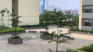 A courtyard with potted trees and a paved walkway, surrounded by modern buildings. - Best Choice And Comfy 2Br Daan Mogot City Apartment (Jakarta)