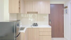 A kitchen with light wooden cabinets, a stainless steel refrigerator, and a gas stove. - Best Choice And Comfy 2Br Daan Mogot City Apartment (Jakarta)