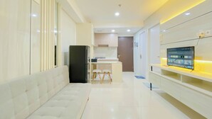 A modern kitchen with a built-in refrigerator, a dining area with stools, and a TV mounted on the wall. - Brand New And Modern 2Br At Daan Mogot City Apartment (Jakarta)