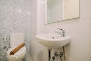 Een badkamer met toilet, wastafel en spiegel.