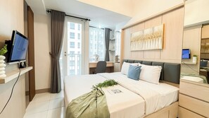 A modern hotel room with a bed, desk, and TV. - Good And Homey Studio Apartment At Tokyo Riverside Pik 2 (Teluknaga)