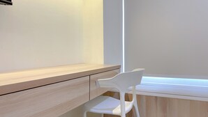 A modern, minimalist room with a wooden desk and a white chair. - Simply Studio Pollux Chadstone Apartment (Cikarang)