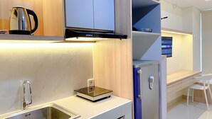 A modern kitchen with a built-in stove, a sink, and a refrigerator. - Simply Studio Pollux Chadstone Apartment (Cikarang)