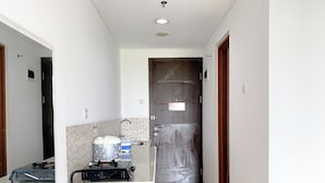 A narrow hallway with a kitchenette area featuring a gas stove, a kettle, and a sink.