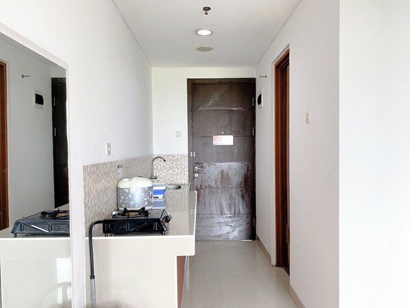Un pasillo estrecho con un área de kitchenette que incluye una estufa a gas, un hervidor y un lavabo.