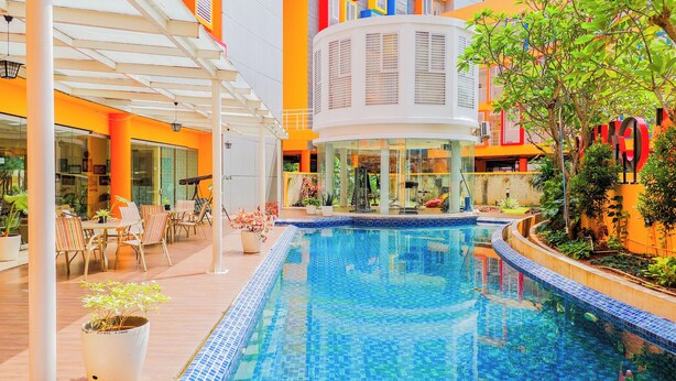 An indoor swimming pool with a tiled floor, surrounded by lounge chairs and a covered seating area. - Good Deal Studio Loft Mezzanine (No Kitchen) At Kubikahomy Apartment (Pagedangan)