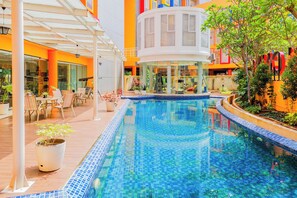 An indoor swimming pool with a tiled floor, surrounded by lounge chairs and a covered seating area. - Good Deal Studio Loft Mezzanine (No Kitchen) At Kubikahomy Apartment (Pagedangan)