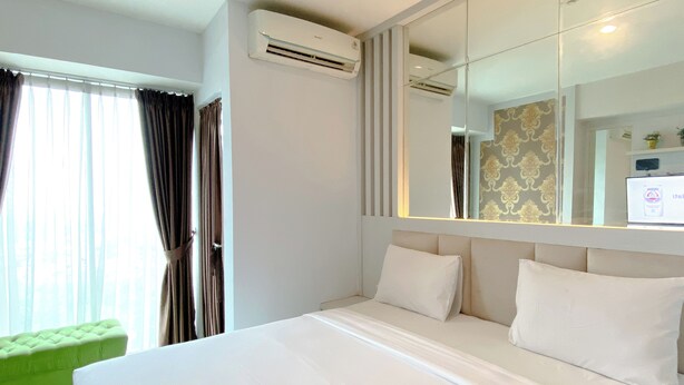 Ein Hotelzimmer mit einem großen Bett, einem grünen Sessel und einem Spiegel, der den Raum widerspiegelt.