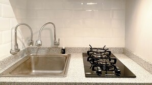 Eine Küche mit Spüle aus Edelstahl, zwei Wasserhähnen und einem schwarzen Kochfeldofen.