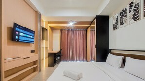 Ein modernes Hotelzimmer mit einem großen Bett, einem Flachbildfernseher an der Wand und einem Schreibtisch mit Stuhl.