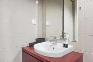Une salle de bain moderne avec un lavabo blanc, un miroir et un meuble-lavabo en bois.