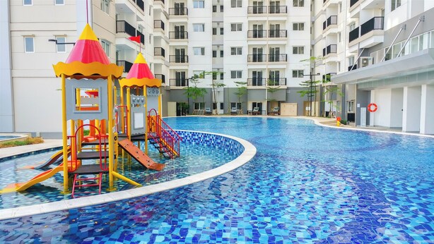 A swimming pool with a slide and play structures, surrounded by a multi-story building with balconies. - Good Choice And Homey 2Br Signature Park Grande Apartment (Jakarta)