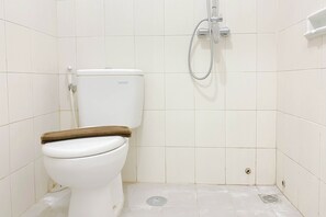Bathroom features a toilet and shower area with a tiled floor.