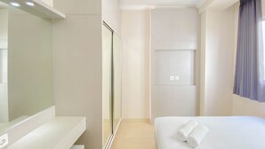 A hotel room with a bed, a mirror, a wardrobe, and a window with curtains. - Good Choice And Homey 2Br Signature Park Grande Apartment (Jakarta)