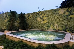 Relax in a serene hot tub surrounded by lush greenery and a beautifully landscaped garden.