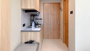 Cozinha compacta com fogão embutido, uma garrafa de água no balcão e uma porta de madeira ao fundo.