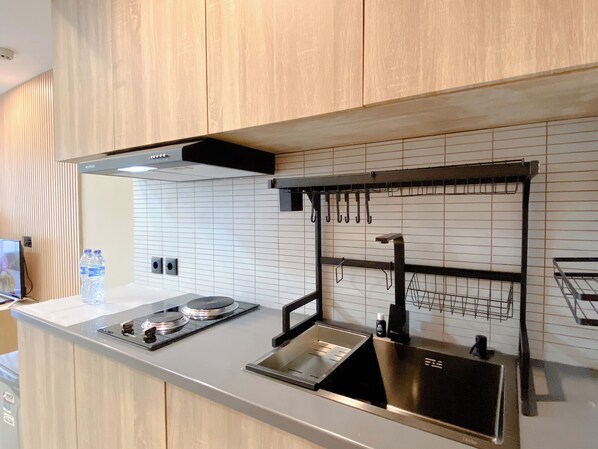 Una cocina moderna con encimera de acero inoxidable, extractor de aire negro y un colgador para utensilios.