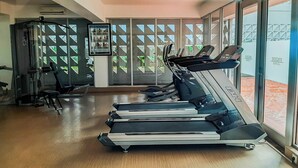 A gym with treadmills, a weight machine, and a wall-mounted TV.