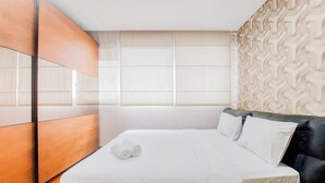 A modern hotel room with a large bed, a wooden headboard, and a patterned wall.