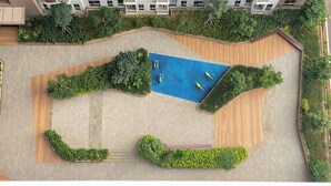 An aerial view of a landscaped courtyard with a swimming pool, surrounded by greenery and wooden walkways. - Comfy And Best Deal Studio At Tokyo Riverside Pik 2 Apartment (Teluknaga)