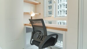 A modern office chair with a mesh backrest and armrests, positioned near a window with a view of a multi-story building. - Comfy And Best Deal Studio At Tokyo Riverside Pik 2 Apartment (Teluknaga)