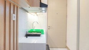 A compact kitchen with a white countertop, a green sink, and a beige door. - Comfy And Best Deal Studio At Tokyo Riverside Pik 2 Apartment (Teluknaga)