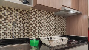 A kitchen with a tiled backsplash, a stainless steel sink, and a stove. - Best Deal And Homey Studio Apartment Amazana Serpong (South Tangerang)