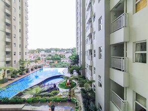 A residential building with a swimming pool surrounded by greenery. - Simple 1Br Apartment Parahyangan Residence (Bandung)