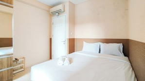 A hotel room with a bed, a wooden wardrobe, a white door, and an air conditioning unit. - Simple 1Br Apartment Parahyangan Residence (Bandung)