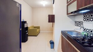 A compact kitchen with a refrigerator, sink, and stove. A small trash bin is visible near the sink. - Simple 1Br Apartment Parahyangan Residence (Bandung)