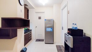 A compact kitchen with a refrigerator, a microwave, and a water dispenser. - Simple 1Br Apartment Parahyangan Residence (Bandung)