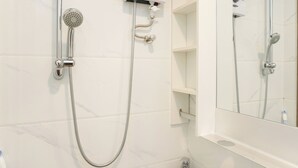 Ein Badezimmer mit Dusche, Toilette und Spiegel.