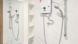 A modern bathroom with a glass-enclosed shower, a built-in toilet, and a white tiled wall. - Furnished And Cozy Studio Sky House Alam Sutera Apartment (Tangerang)