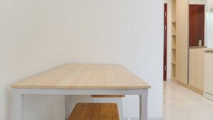 A small, simple room with a wooden table and bench, a white wall, and a wooden cabinet in the background. - Furnished And Cozy Studio Sky House Alam Sutera Apartment (Tangerang)