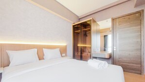 A hotel room with a large bed, a walk-in closet, and a mirror.
