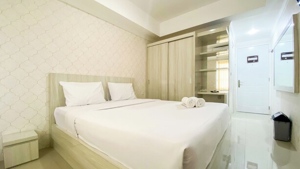 A hotel room with a large bed, a wardrobe, a mirror, and a small trash bin. - Cozy And Minimalist Studio Paltrow City Apartment (Semarang)