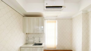 A small, compact room with a kitchenette, a single bed, and a window with blinds. - Cozy And Minimalist Studio Paltrow City Apartment (Semarang)