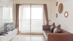 A modern living room with a sofa, a TV, a white console table, and a large window with curtains. - Comfort And Spacious 1Br M-Town Signature Apartment (Gading Serpong)